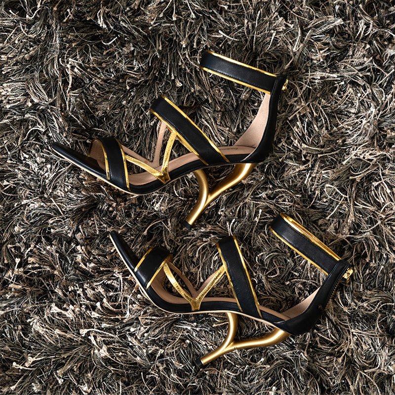 black and gold Alto high heel shoes on dark gray rug